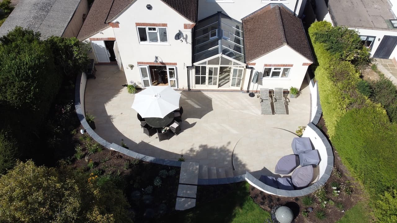 Aerial view of a contemporary curved house with a large circular patio and water feature