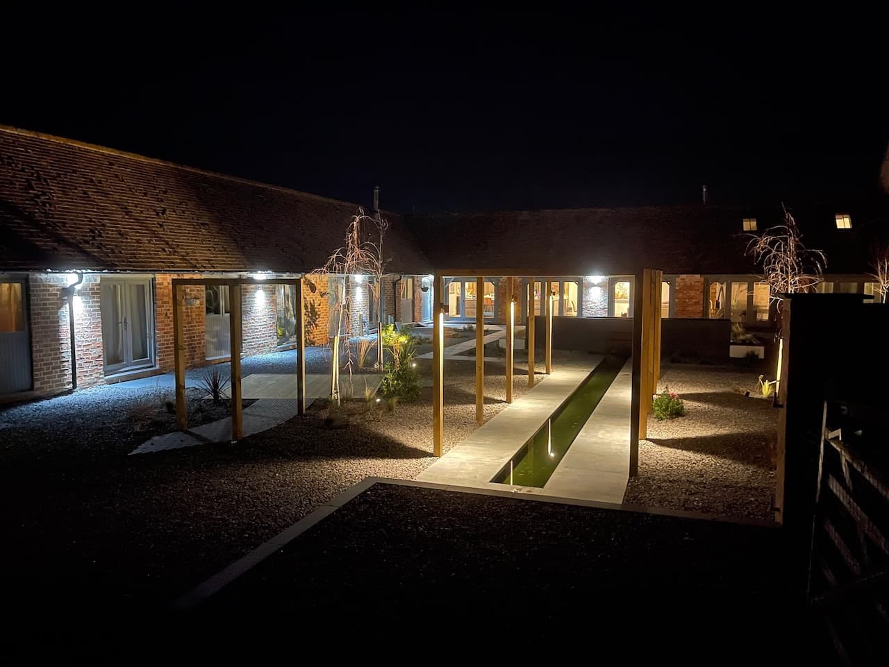 Converted barn courtyard at night with an illuminated sunken fire pit