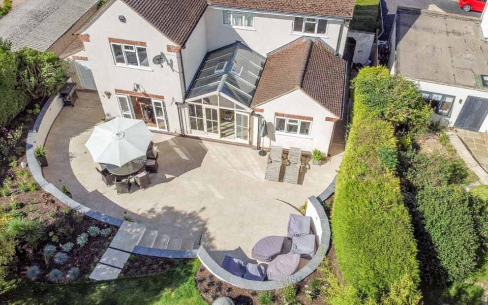 Large entertaining patio with expansive paved seating area set among mature planting
