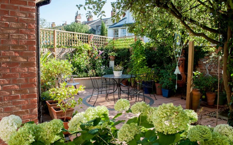 Small town garden transformed into a secluded planted haven with paving and water feature